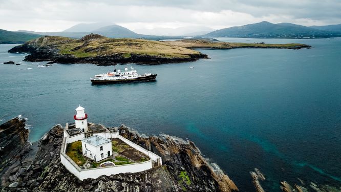 An aerial view of Valentia Island lighthouse with the ship, the Serenissima, sailing into to port.